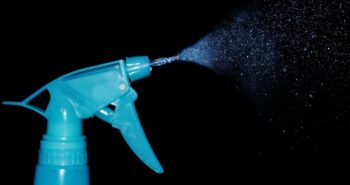 Blue spray bottle spraying cleaning solution