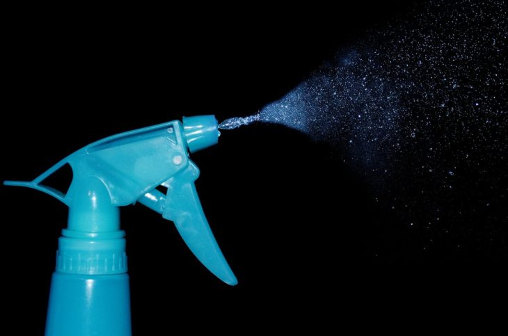 Blue spray bottle spraying cleaning solution